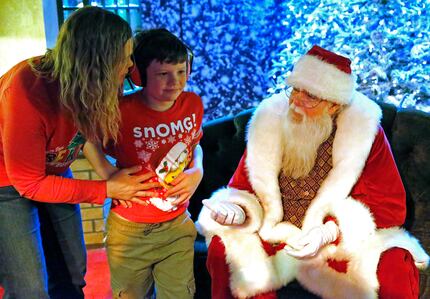 Leslie Griggs of McKinney comforts her son Jack, 10, so that he can sit with Santa during a...