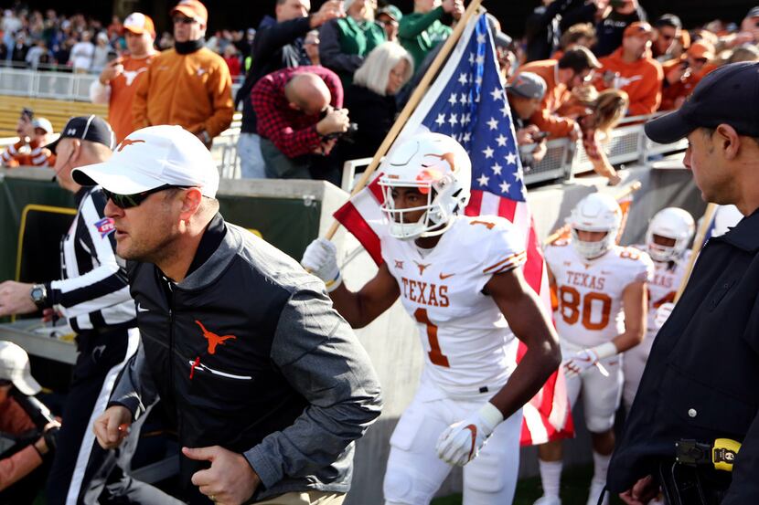 FILE - In this Oct. 28, 2017, file photo, Texas head coach Tom Herman, left, runs on the...