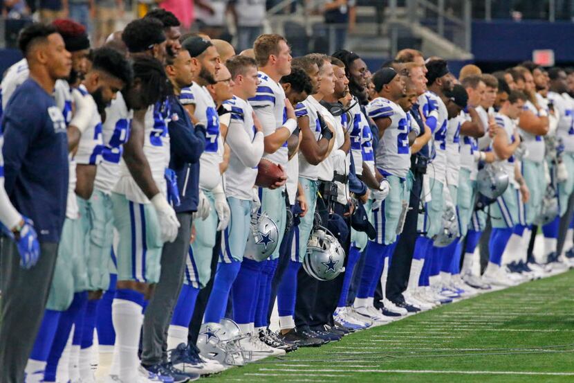The Cowboys stand together on the sidelines during the national anthem before the Green Bay...