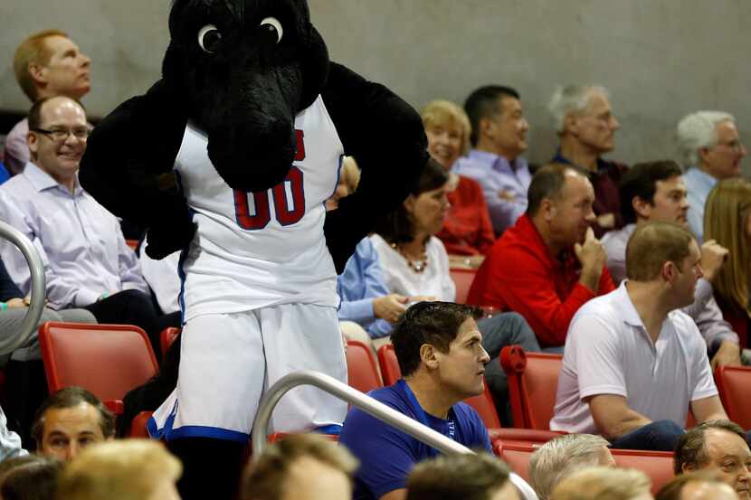 Dallas Mavericks owner Mark Cuban watches the game as the SMU mascot stands behind him in a...