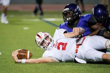 Grapevine Faith quarterback Deuce Hogan (2) stretches the ball for extra yardage after being...