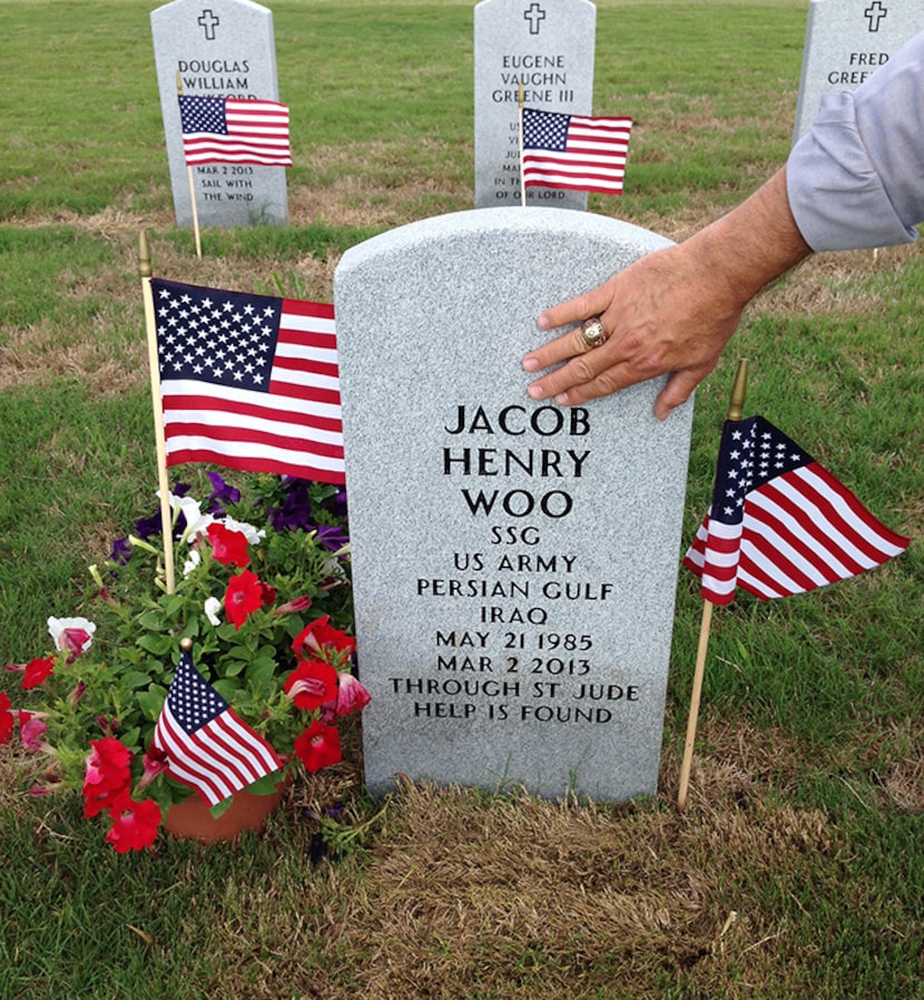  David Woo places his hand on the headstone of his son, Jake, at the Houston National...