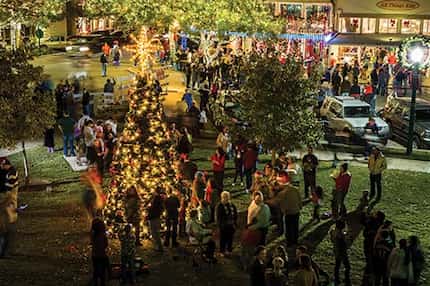 A crowd of people gathering around the town square Christmas tree