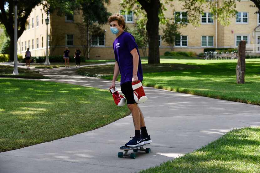 A Texas Christian University student rides a board outside of Clark Hall dormitory on the...