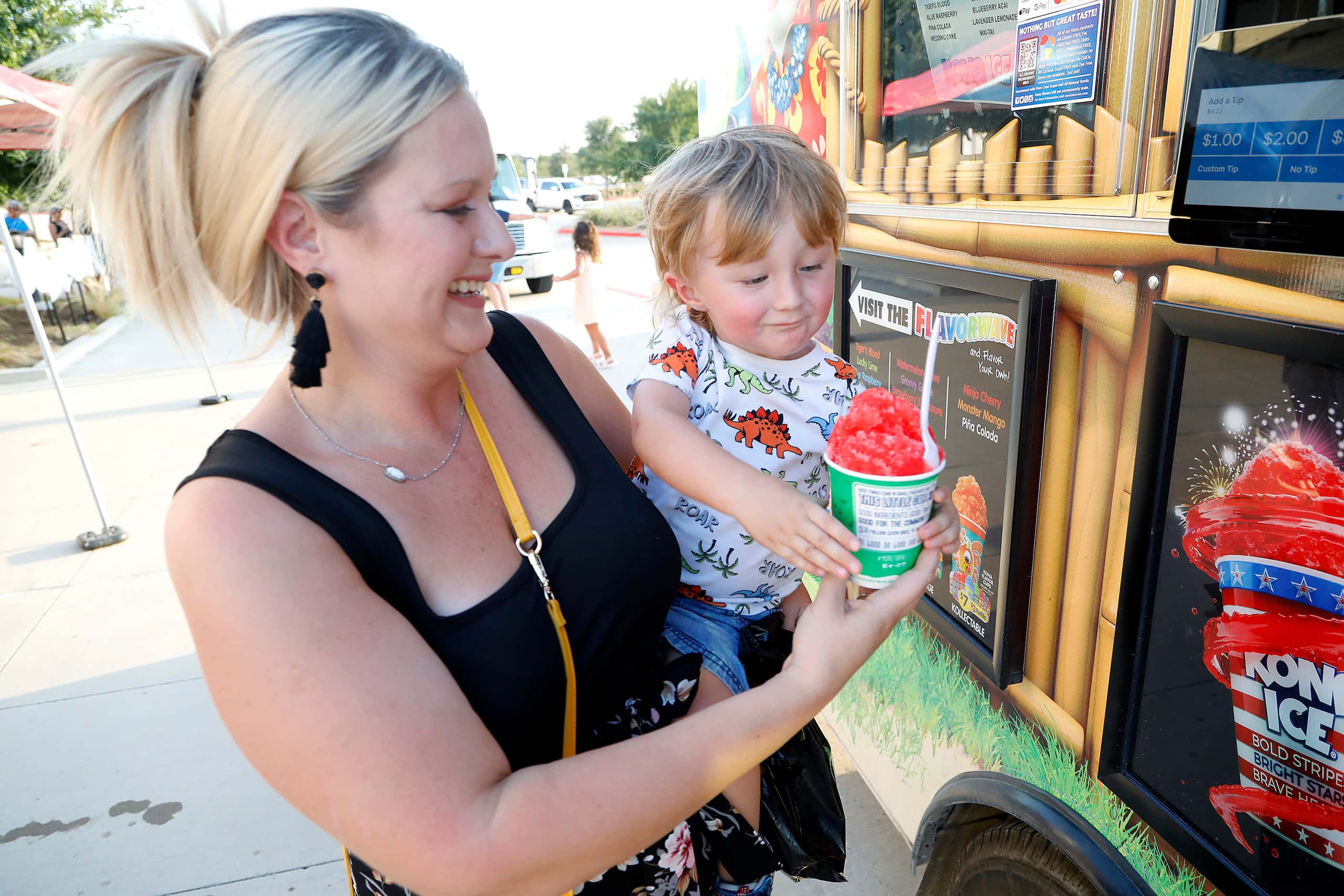 Nicole Danielson (left) of McKinney, holds her son Sven, 2, who is getting a refreshment...