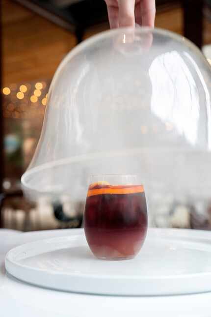 A covering is removed from the smoked sangria drink at Belse Plant Cuisine.