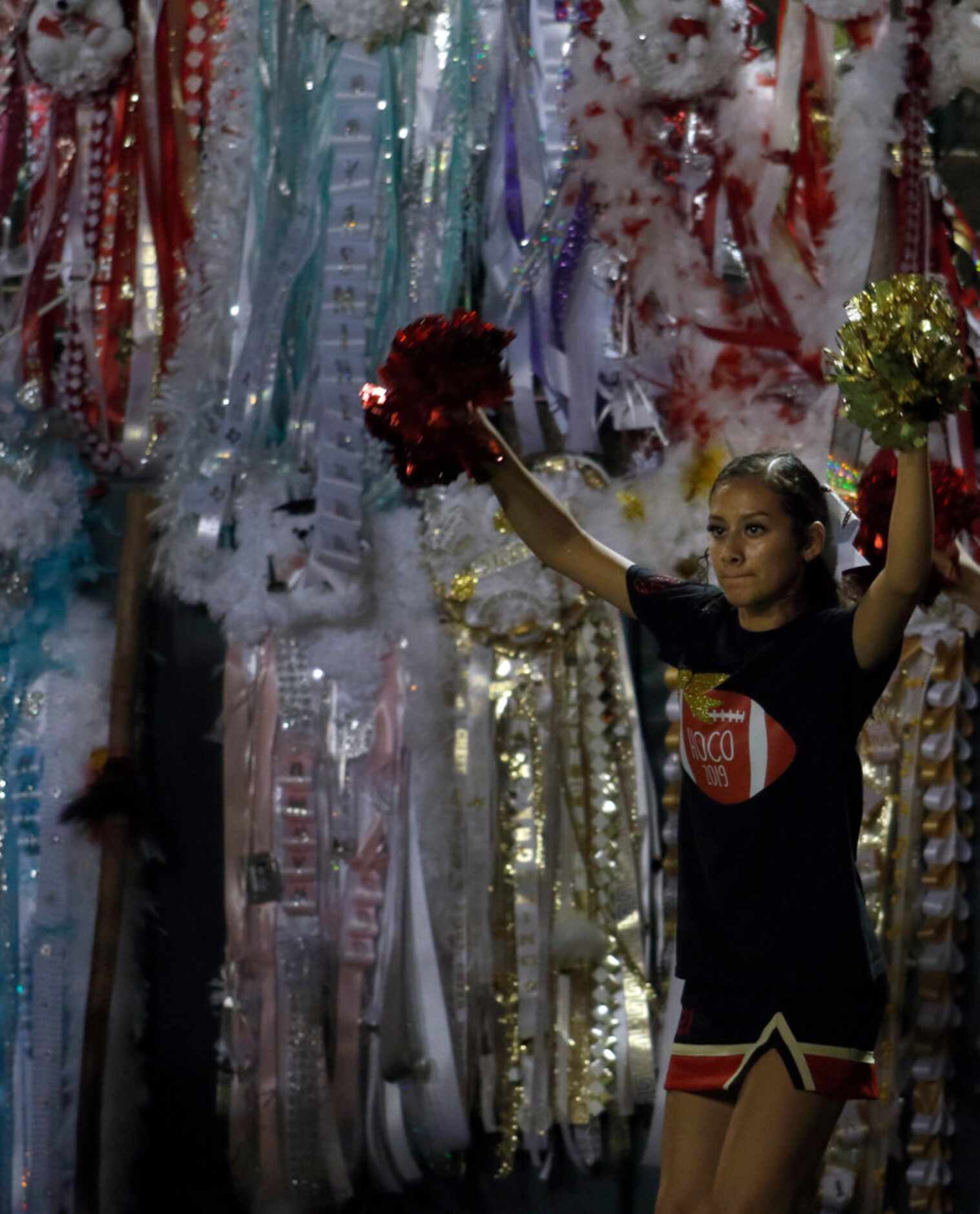 A South Grand Prairie cheerleader cheers a first down against  background of mums during the...