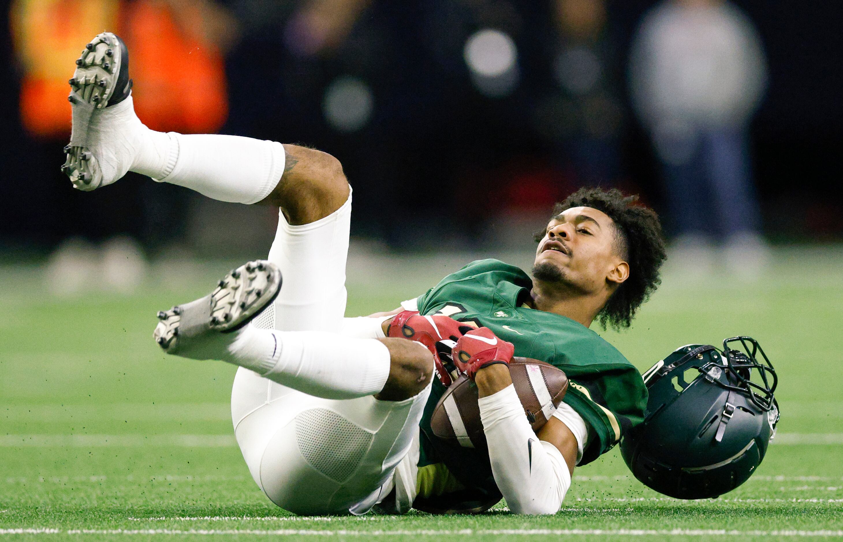 DeSoto’s Cedric Harden Jr. (13) falls to the ground while his helmet flies off after making...
