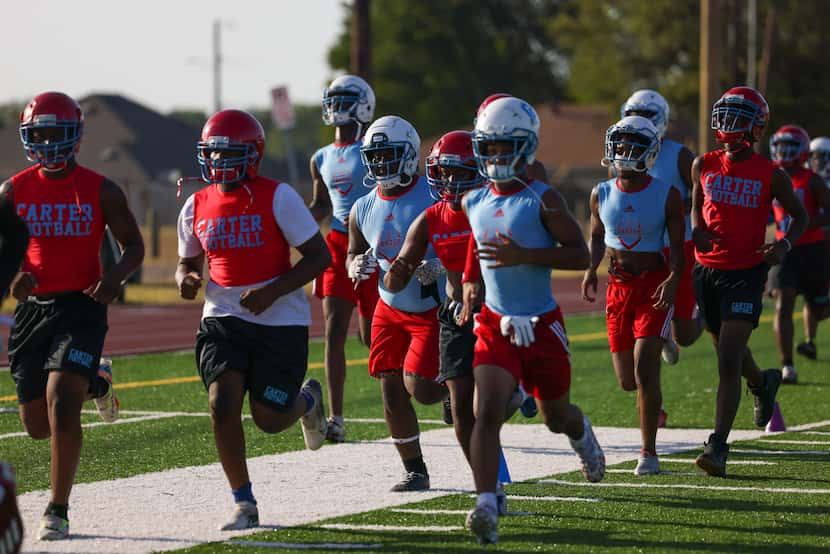 Carter High School football players take a lap around the field during the first practice of...