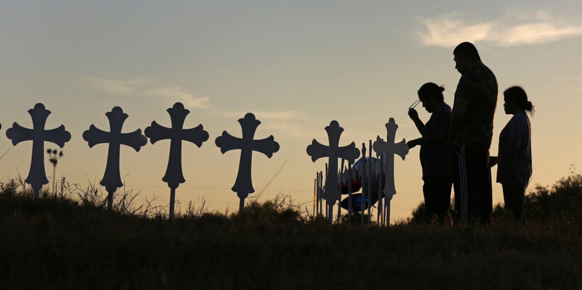 Irene and Kenneth Hernandez and their daughter Miranda Hernandez say a prayer in front of...