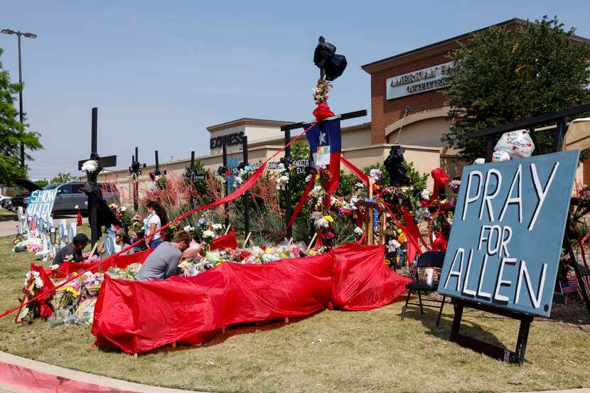 People place flowers and pay their respects at a memorial for victims of the Allen Premium...