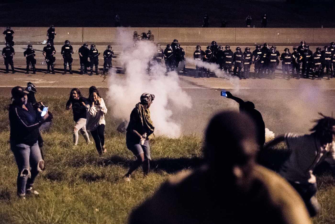 CHARLOTTE, NC - SEPTEMBER 21: Protestors run from a gas canister after blocking traffic  on...