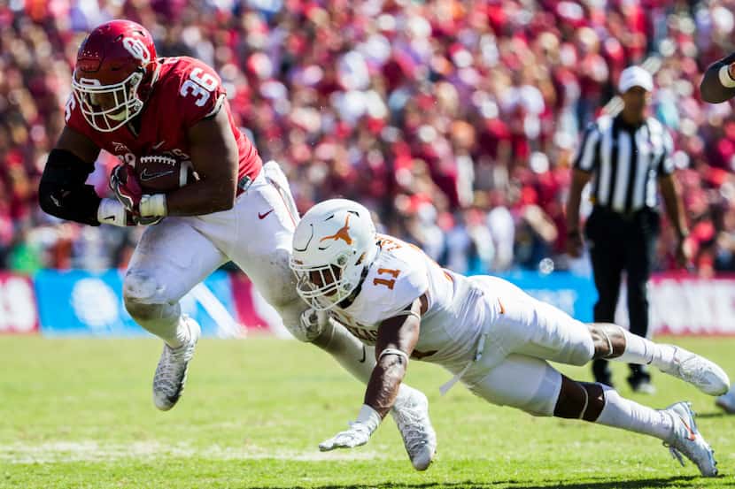 Oklahoma Sooners fullback Dimitri Flowers (36) escapes a a tackle attempt by Texas Longhorns...