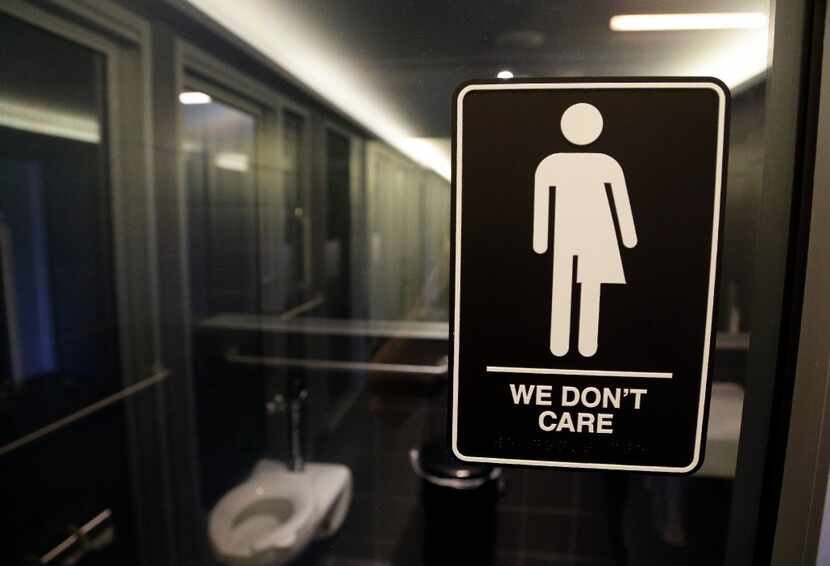 This sign outside a restroom at 21c Museum Hotel in Durham, N.C., reflects one side of the...