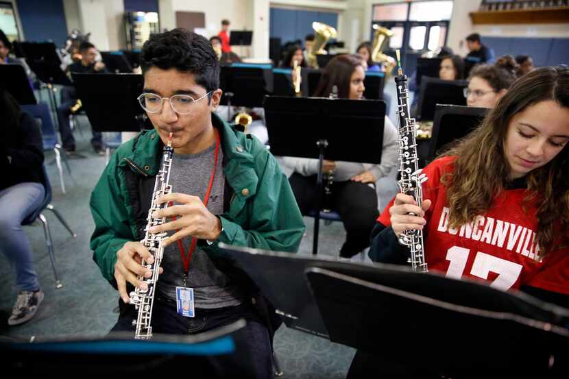 Freshman oboe player David Mojica (left) warms up on his instrument alongside classmate...