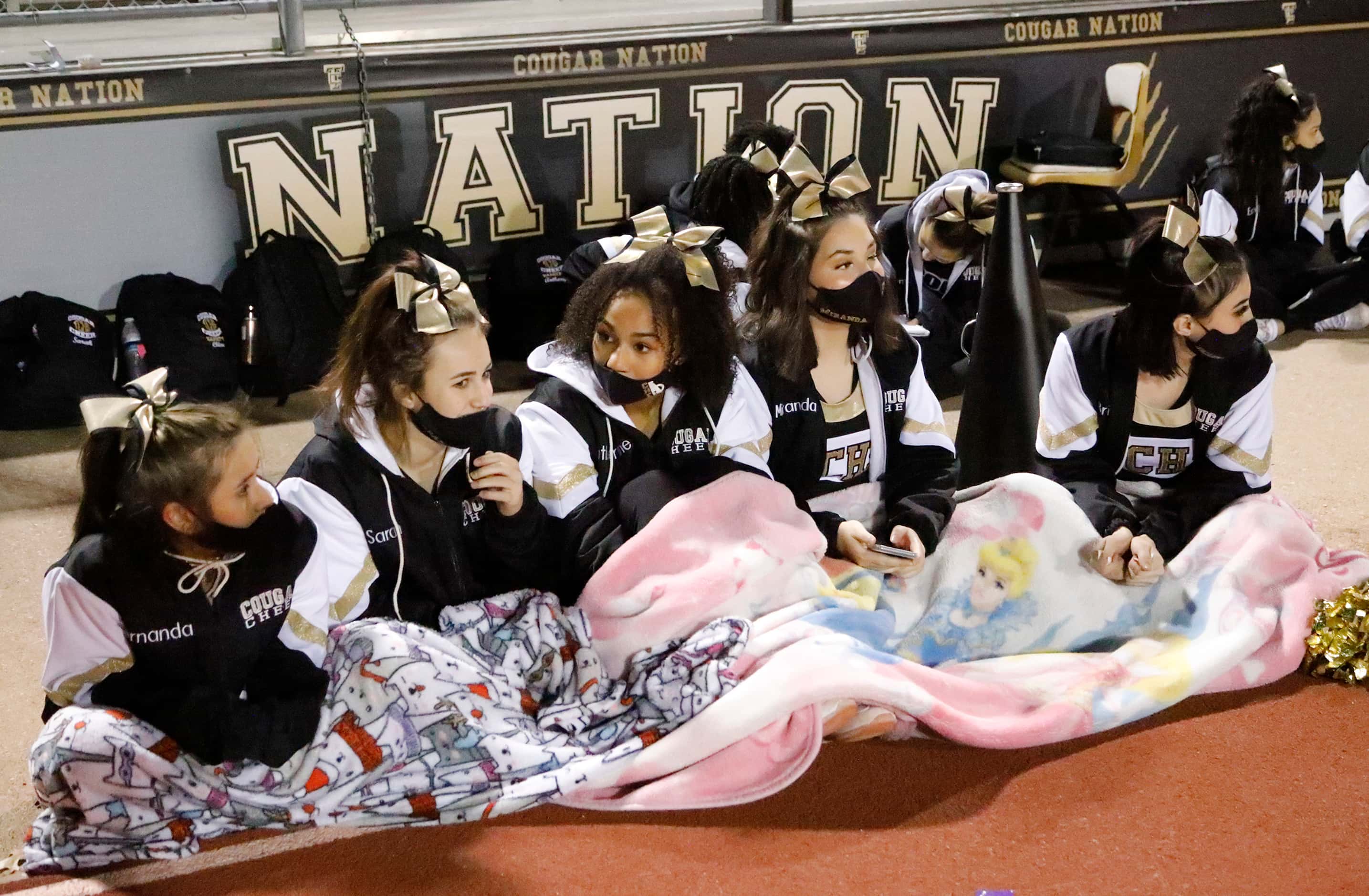The Colony High School cheerleaders huddle for warmth before kickoff  as The Colony High...