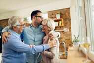 Happy mature couple embracing their adult son while greeting with him in the kitchen.