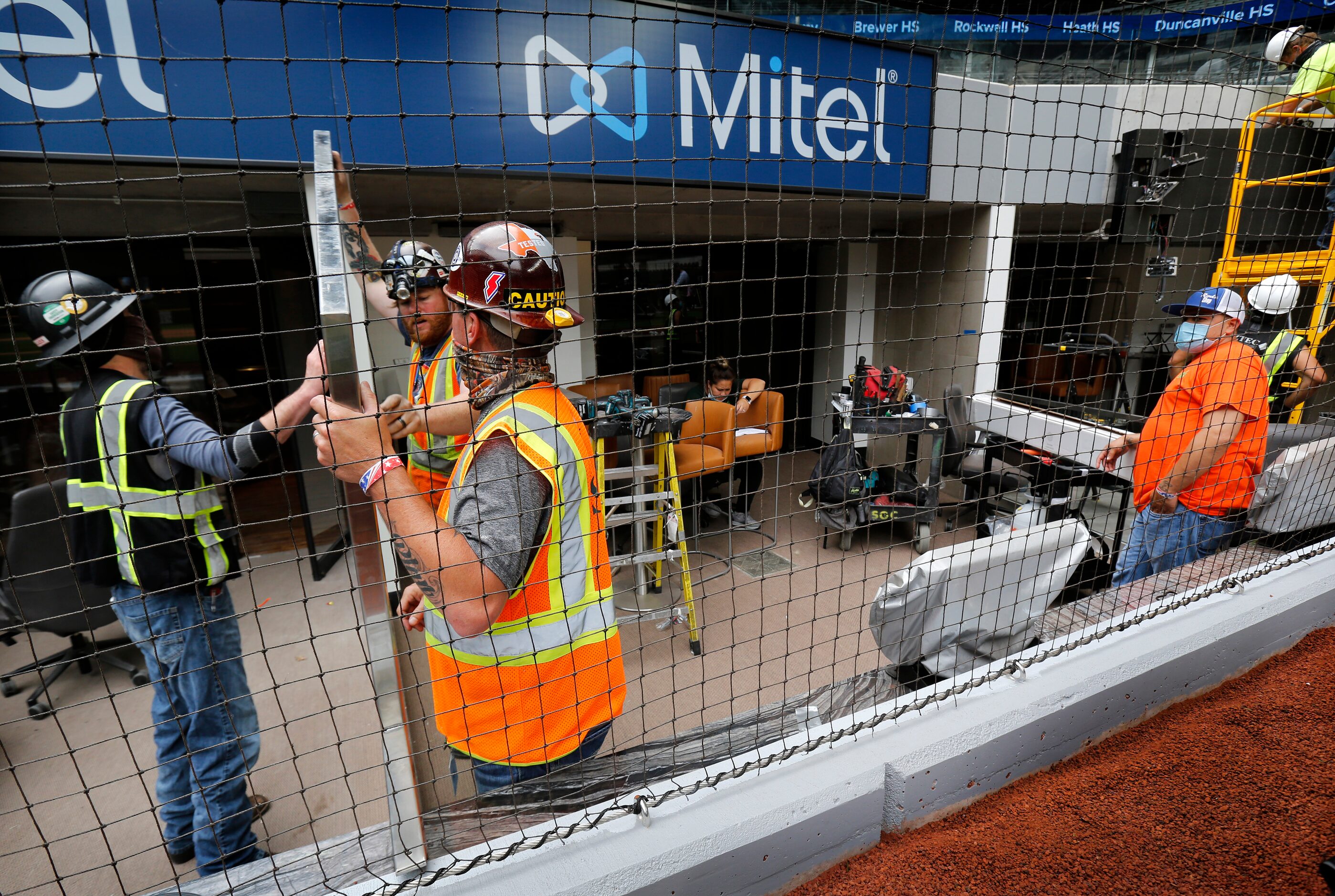 Construction workers finish out the field level suites behind home plate at the newly...