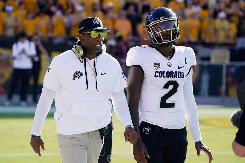 FILE - Colorado head coach Deion Sanders, left, talks with his son and starting quarterback...
