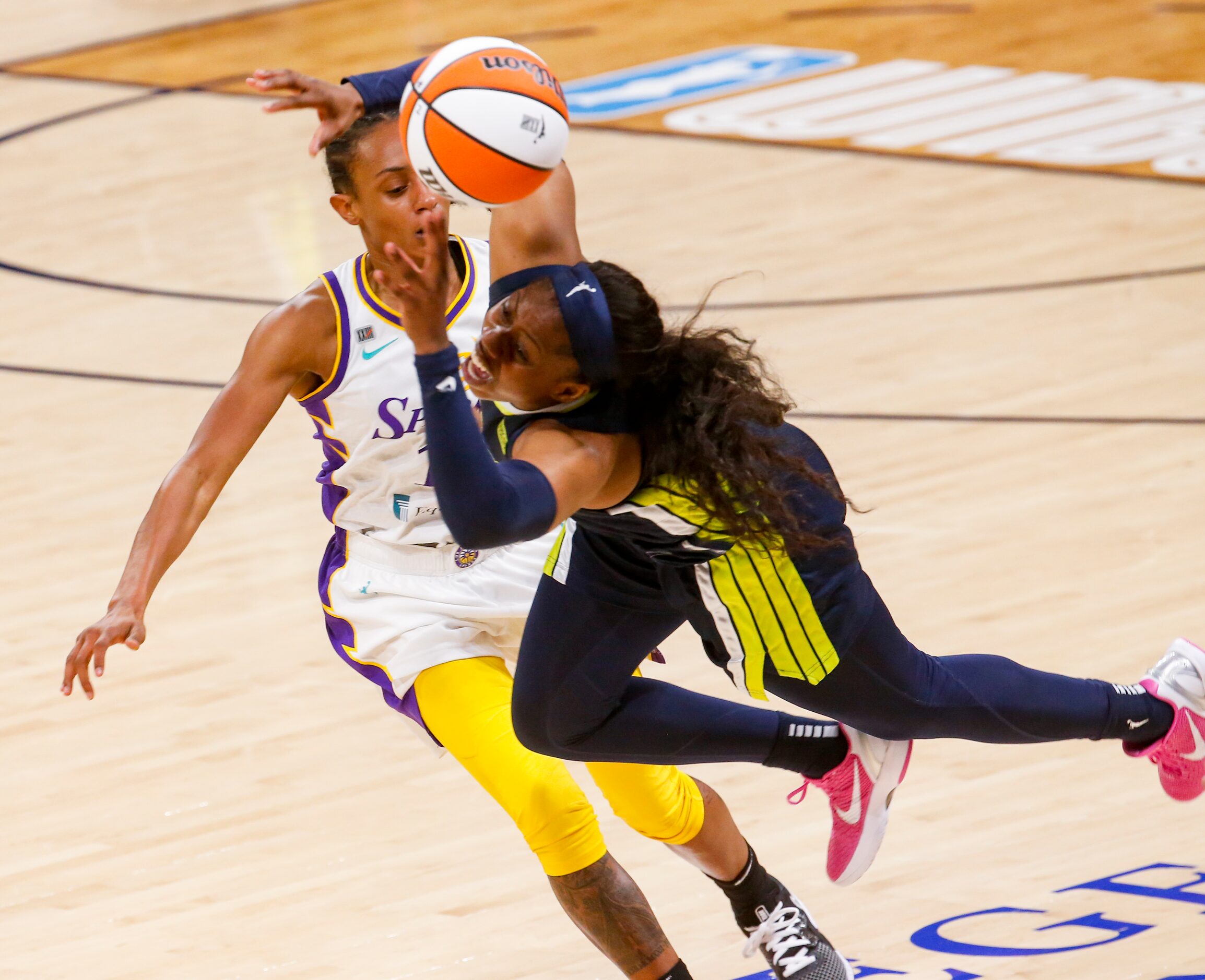 Dallas Wings guard Arike Ogunbowale (24) trips over Los Angeles Sparks guard Brittney Sykes...