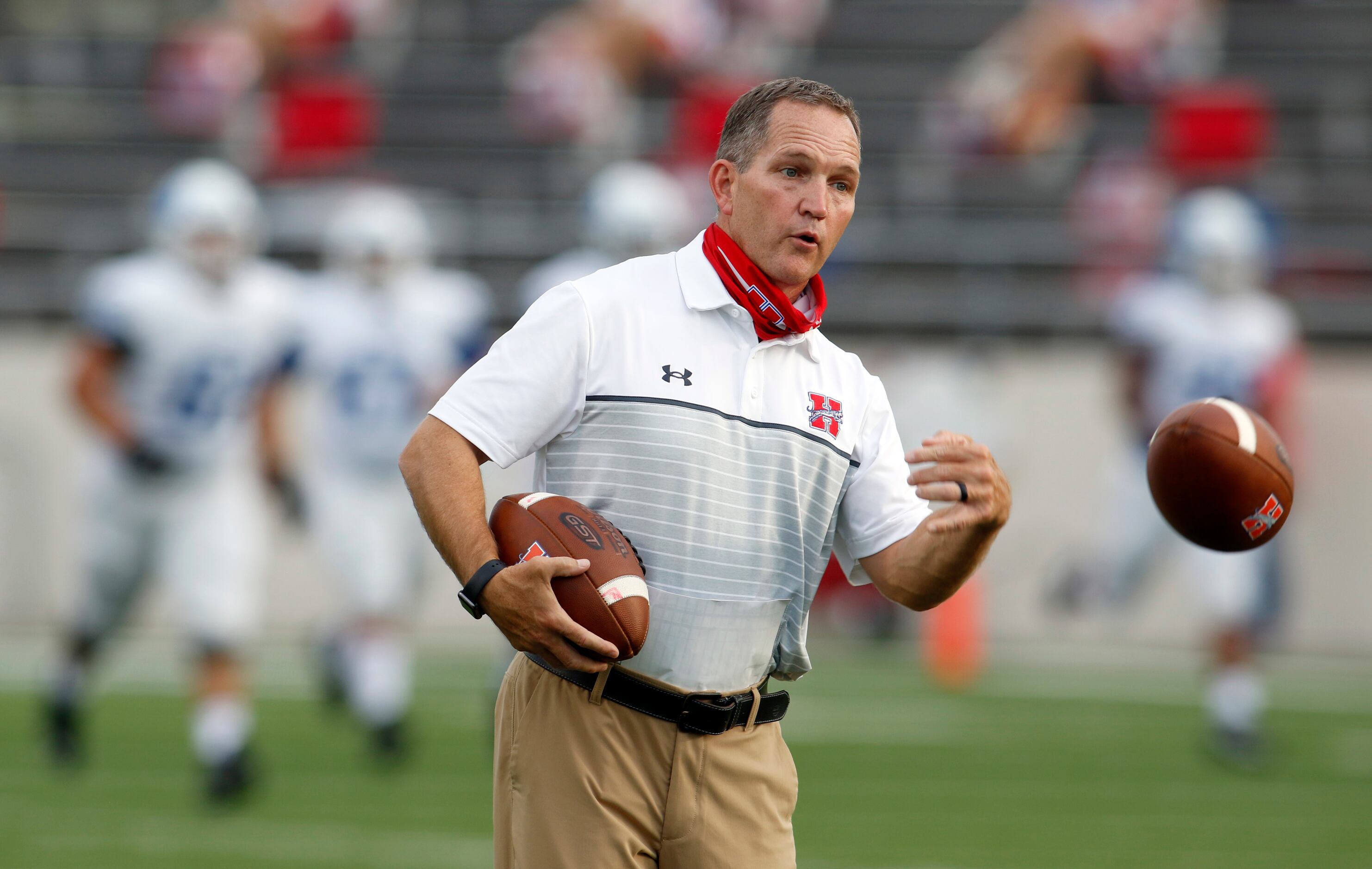 Midlothian Heritage head football coach Lee Wiginton tosses a ball to his players during...