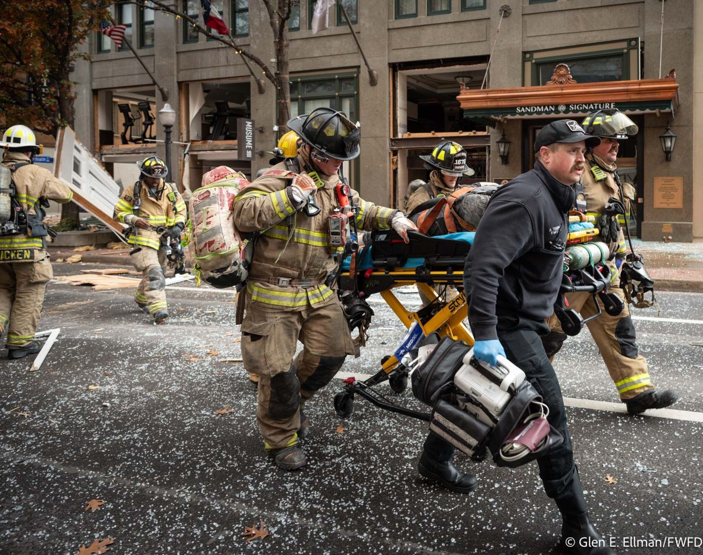 Fort Worth firefighters transport an injured person following an explosion at the Sandman...