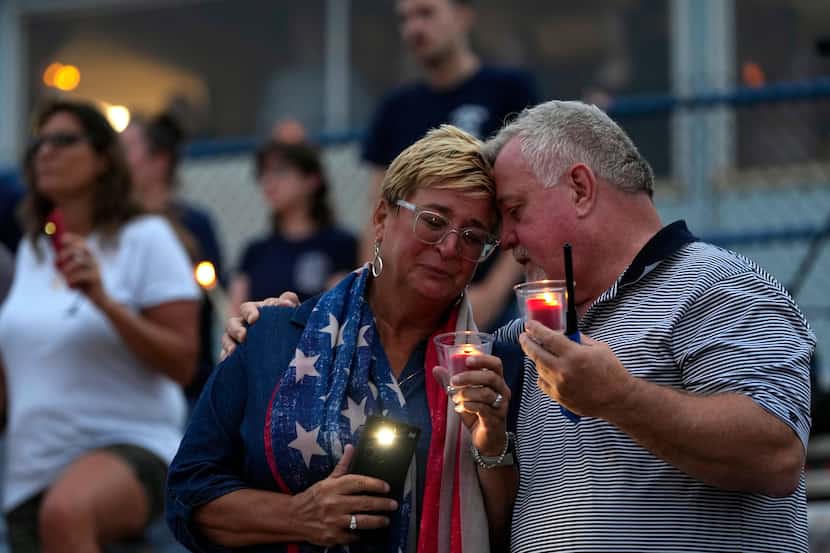 People embrace during a vigil for Corey Comperatore, the former fire chief shot and killed...