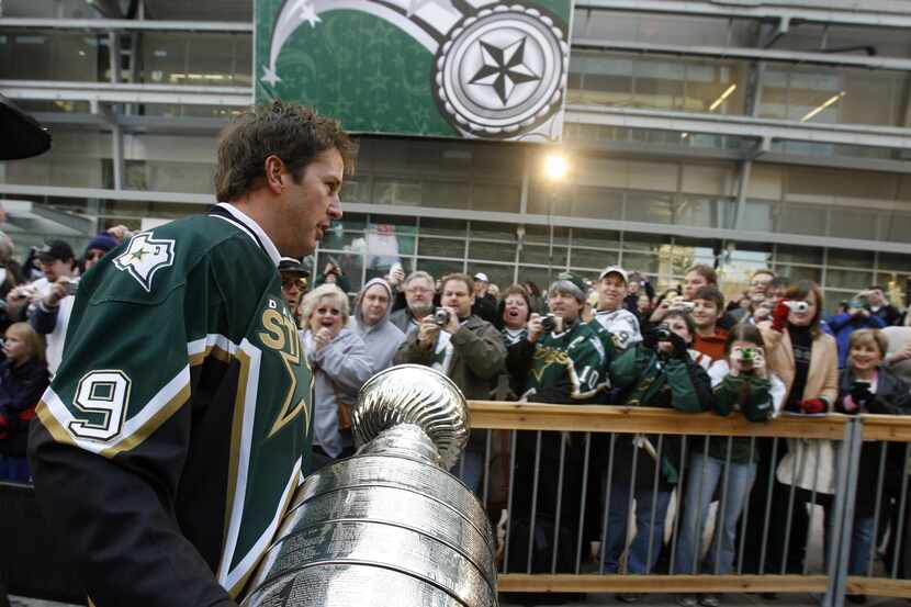 Dallas'  Mike Modano carries the Stanley Cup to the stage along the south plaza area outside...