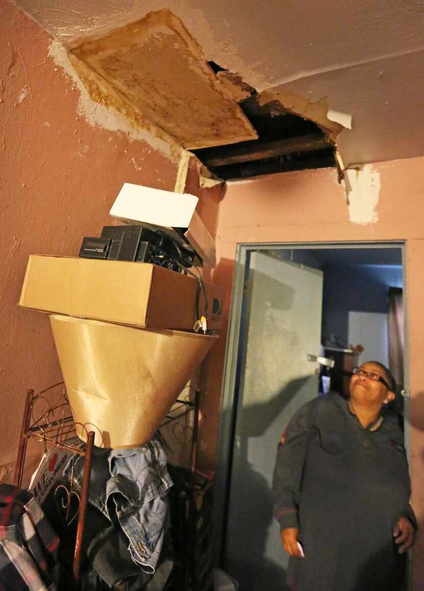 Joanne Bonner looks  through a hole in the ceiling in the Topletz-owned home her family...