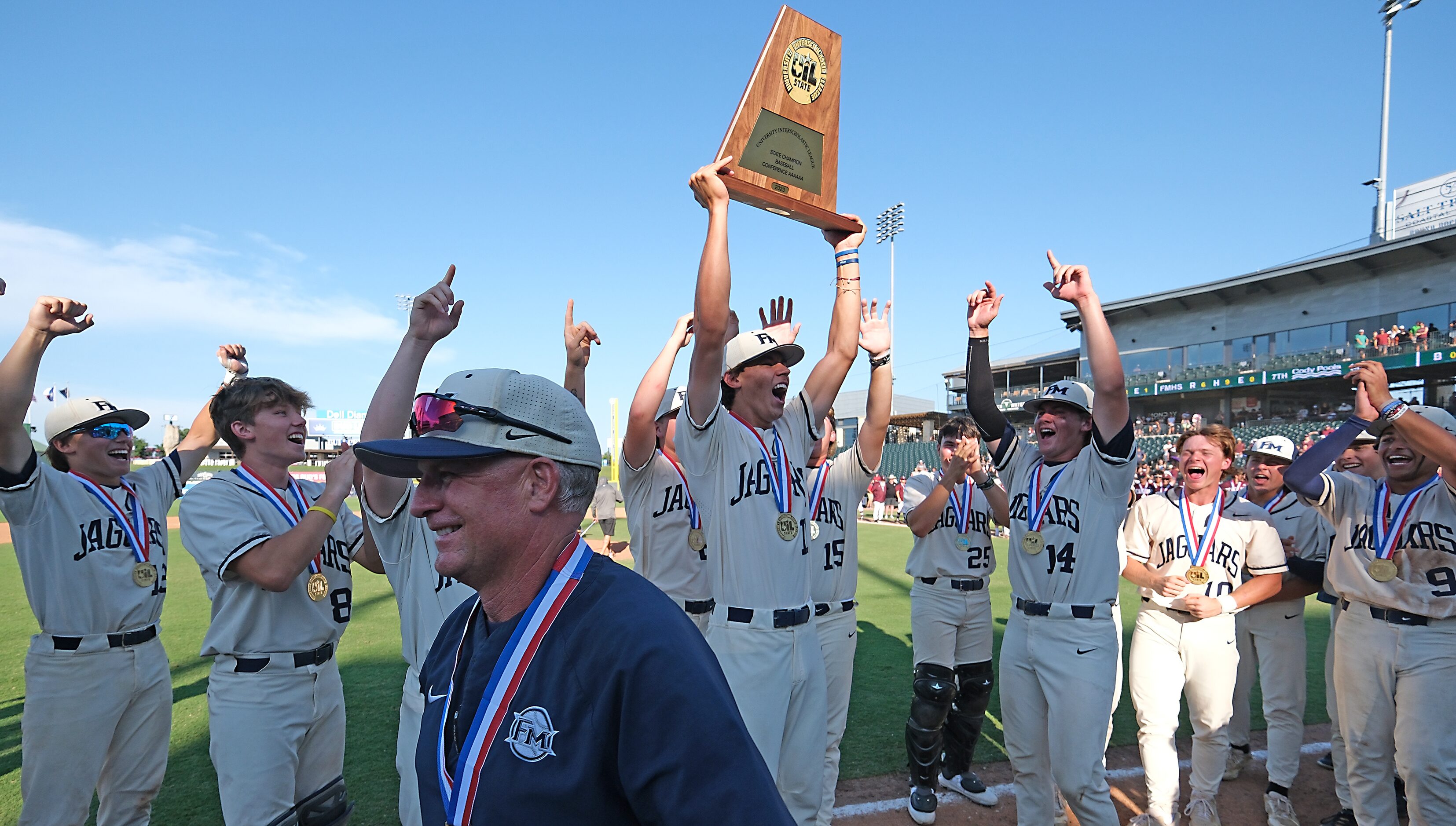 Flower Mound coach, Danny Wallace, passes off the championship trophy to Jacob Gholston,...