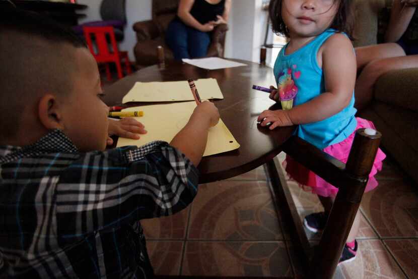 Two children, both from El Salvador, take time to draw in a southern Dallas home. They both...