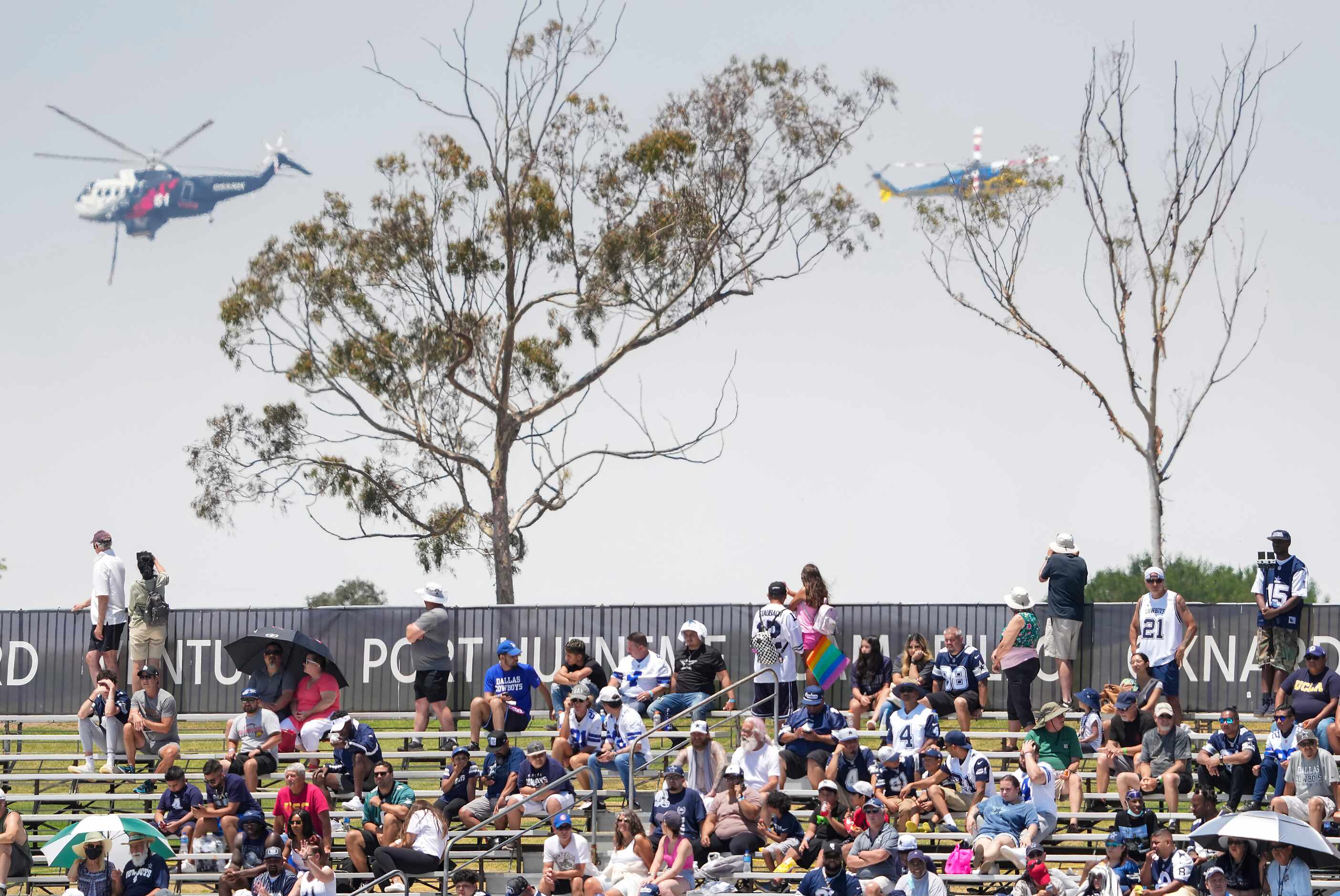 Fans watch as firefighting helicopters work near the facility during Dallas Cowboys practice...