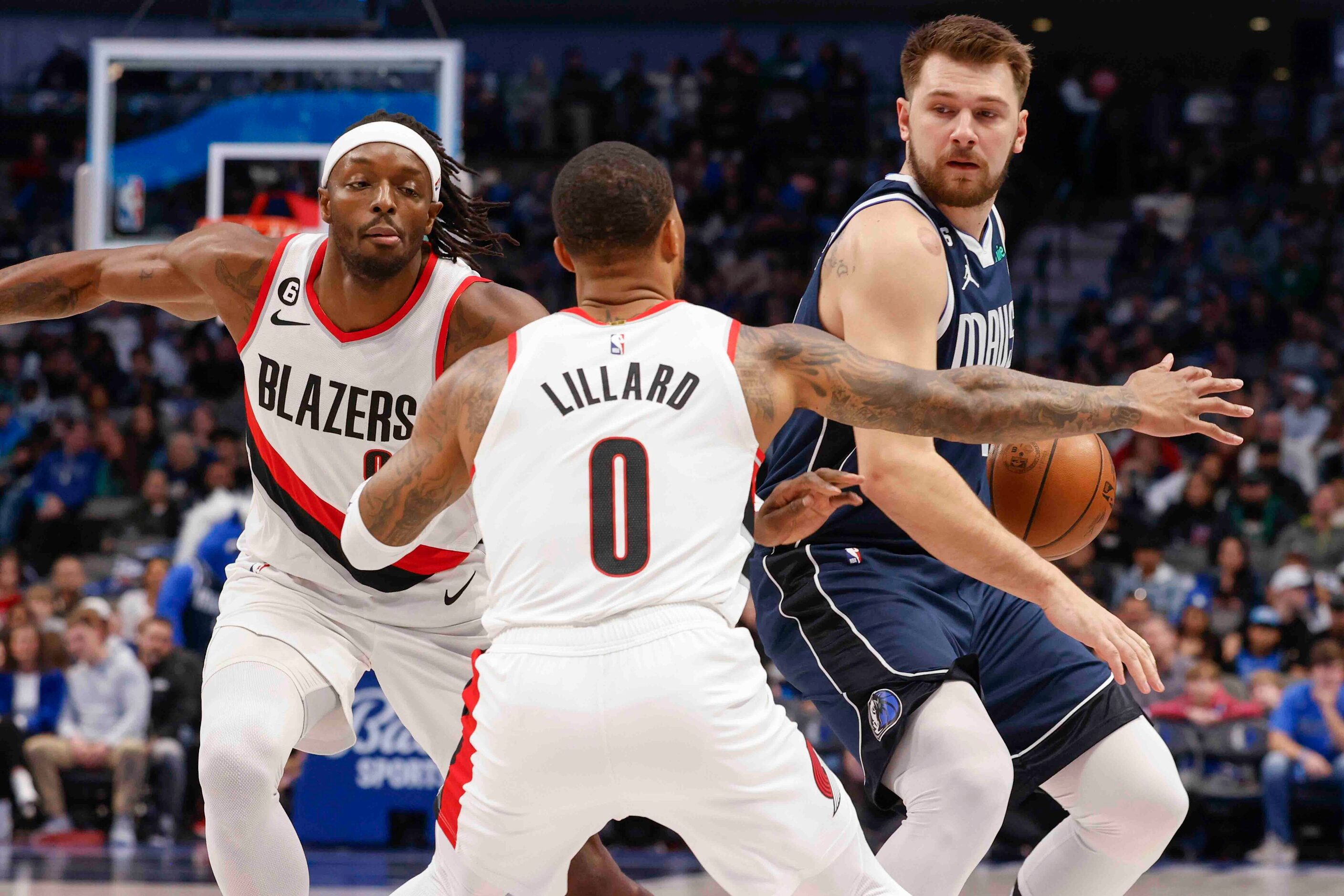 Dallas Mavericks guard Luka Doncic (77), right, looks to pass past Portland Trail Blazers...