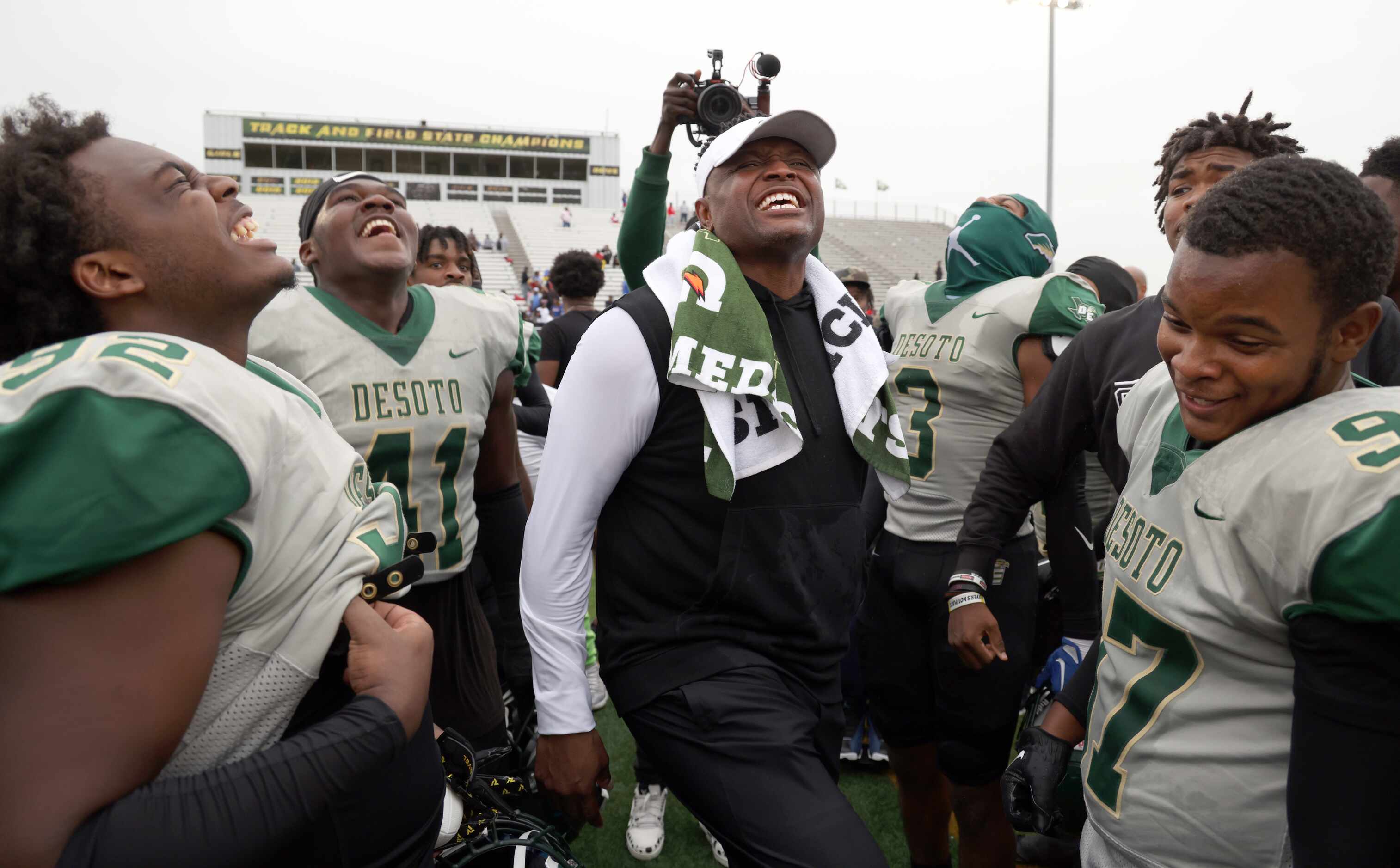 DeSoto head coach Claude Mathis, center, lets out a yell as he celebrates with his players...
