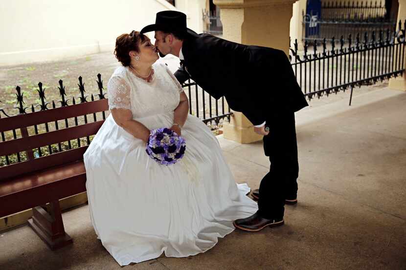 Michael Hull (right) leans over to kiss his soon-to-be bride Michelle Marshall before a mass...