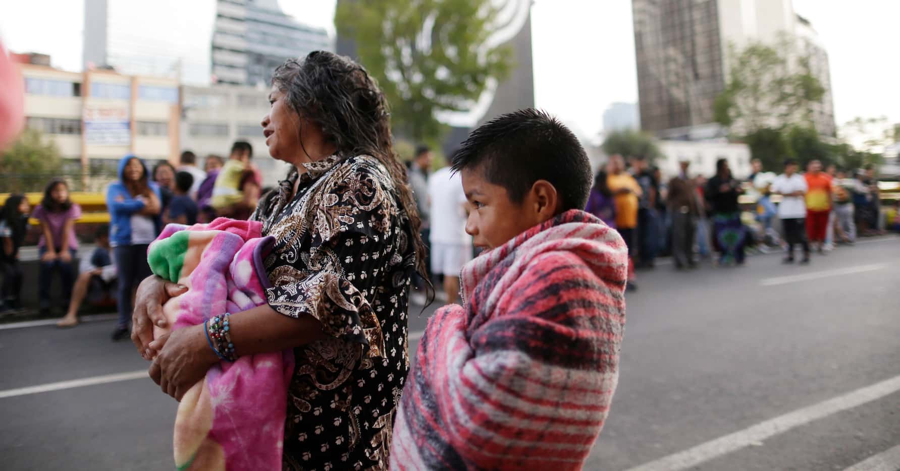 People stand in the street after hearing an earthquake alarm, in Mexico City, Saturday,...