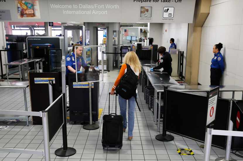 A single passenger makes her way through a TSA security checkpoint at DFW International...