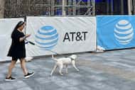 Teresita Gaytan, of Dallas, looks down at her phone while walking her dog Chance at AT&T...