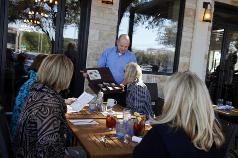 A server offers tea choices to patrons on the patio at Princi Italia in Dallas.