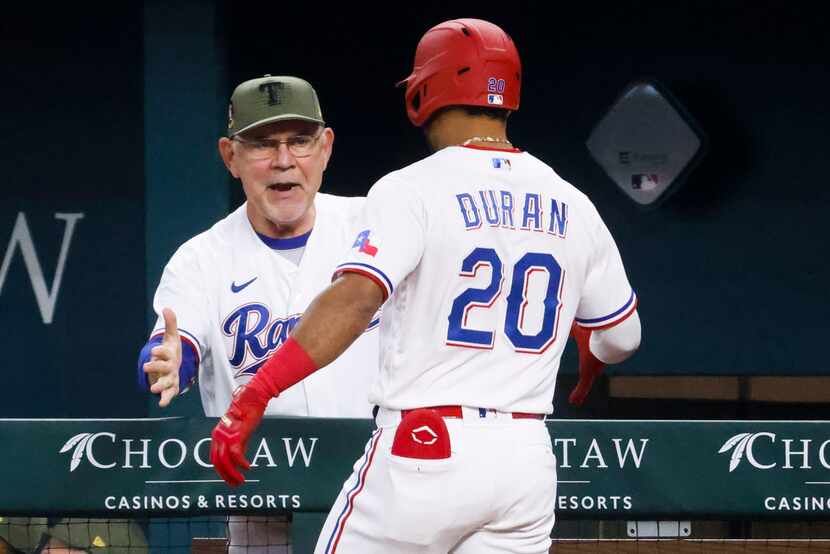 Texas Rangers manager Bruce Bochy (left) cheers with shortstop Ezequiel Duran after a homer...