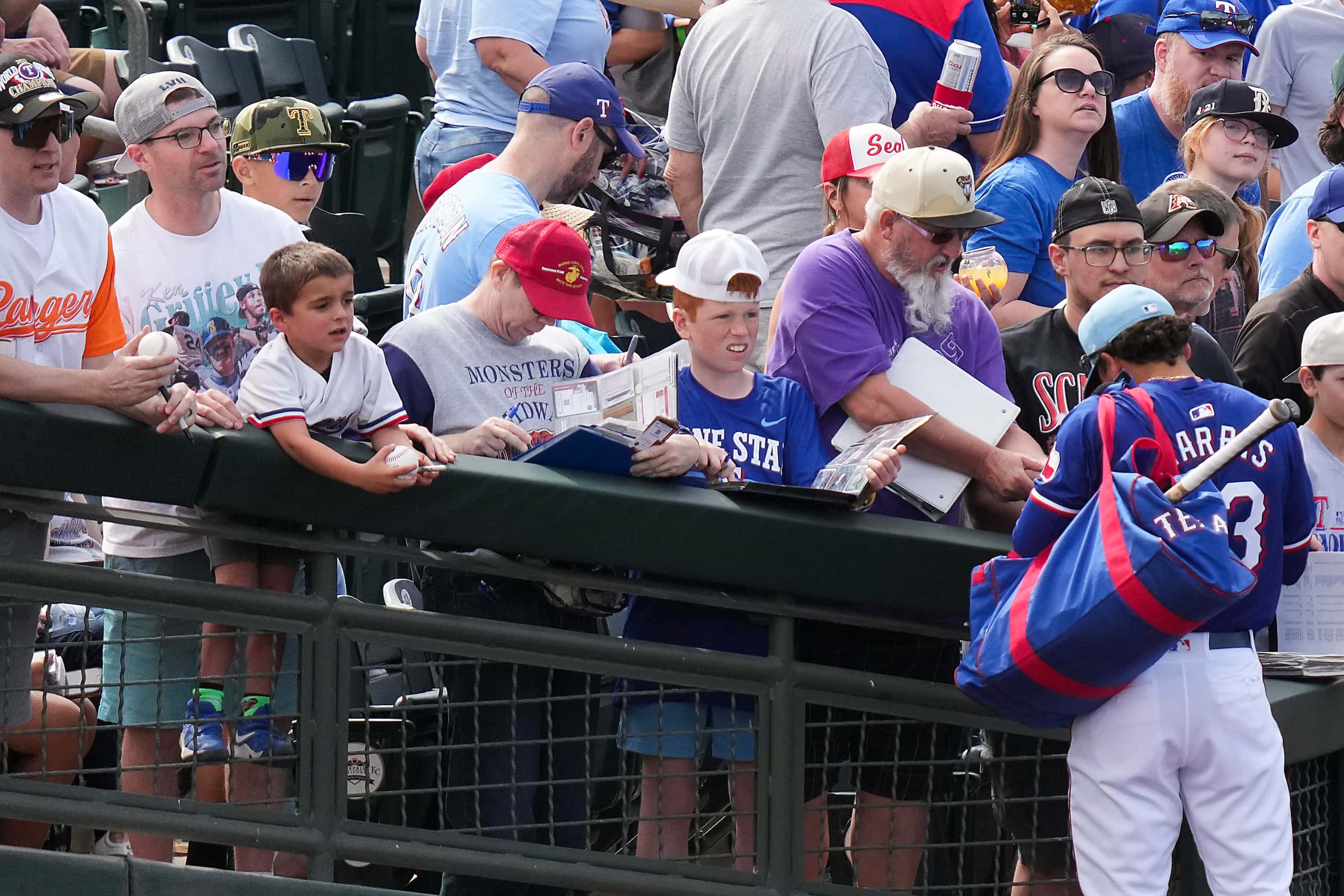 Texas Rangers outfielder Dustin Harris signs autographs before a spring training game...