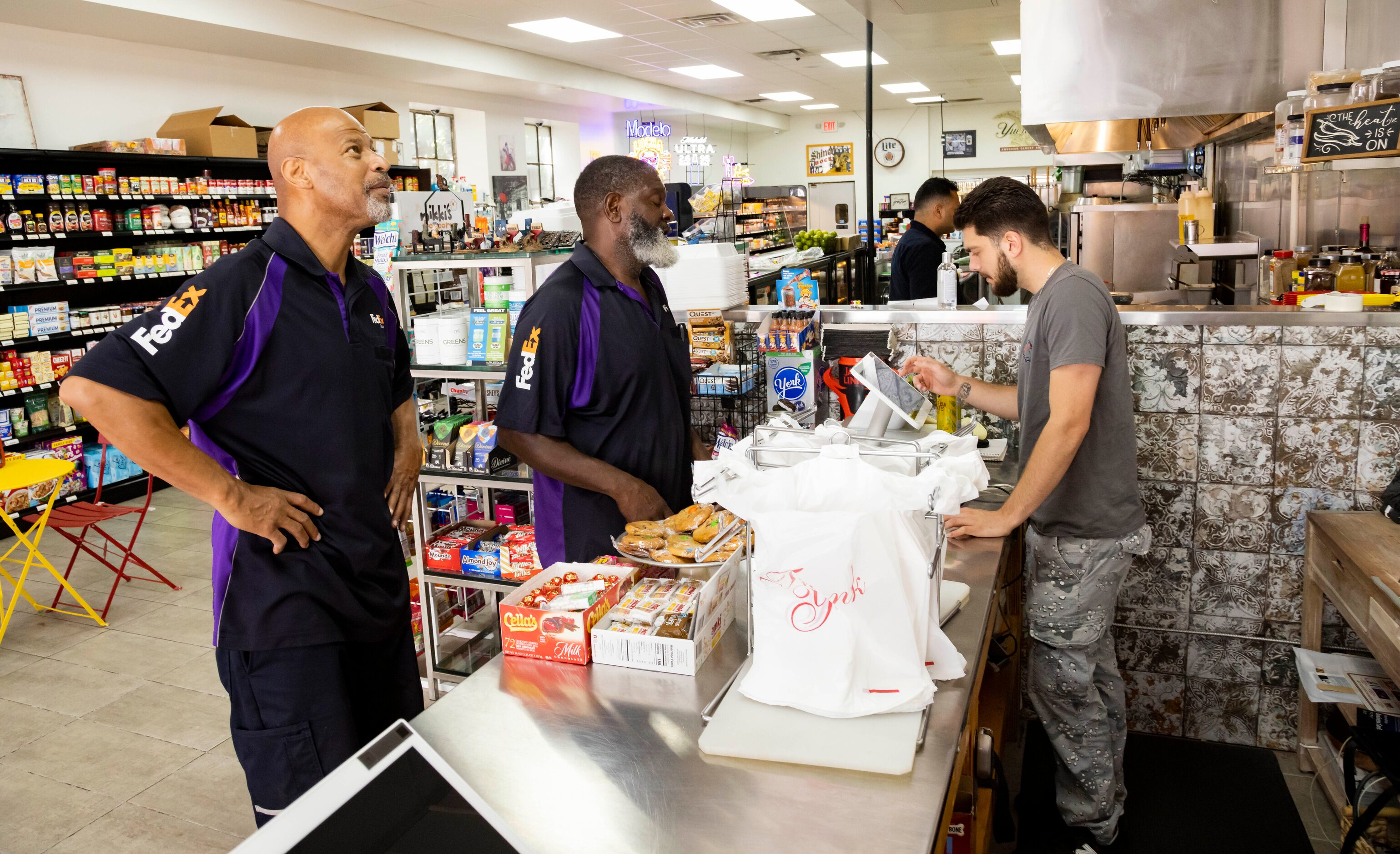 Massimo Murgia takes FedEx drivers Joseph Paul and Greg Wade’s order at Main Street Market...