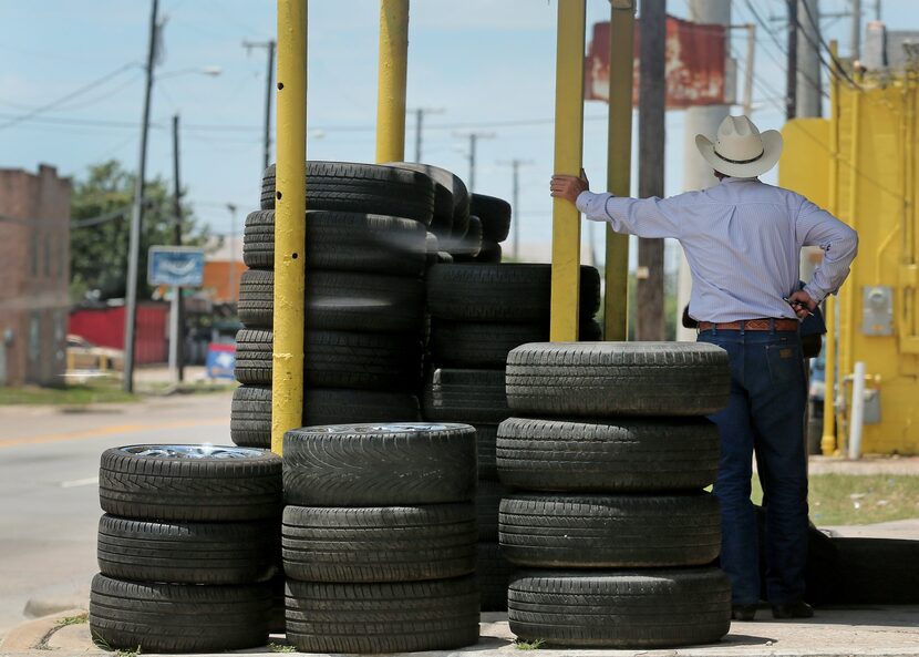 A tire shop employee awaits customers on Singleton Boulevard in West Dallas.