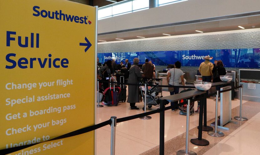 Southwest Airlines passengers wait in line to check in at Dallas Love Field in Dallas,...