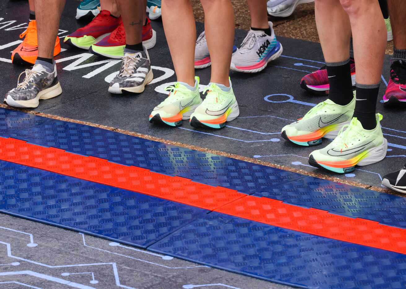 Full marathon runners Megan Taylor and Cameron Beckett stand in matching neon shoes along...