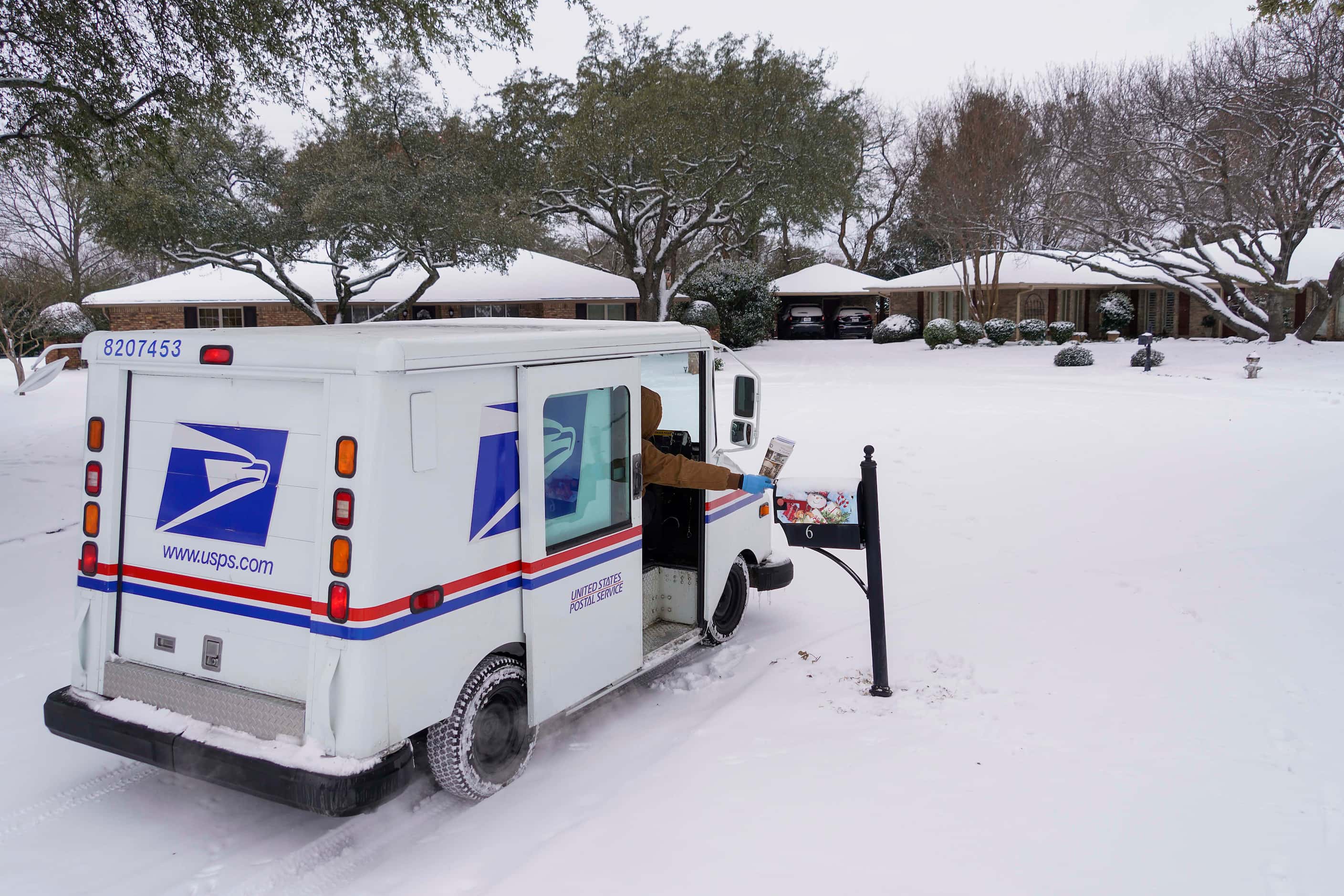 Letter carrier Angel Garcia delivers mail to a snow covered neighborhood after a second...