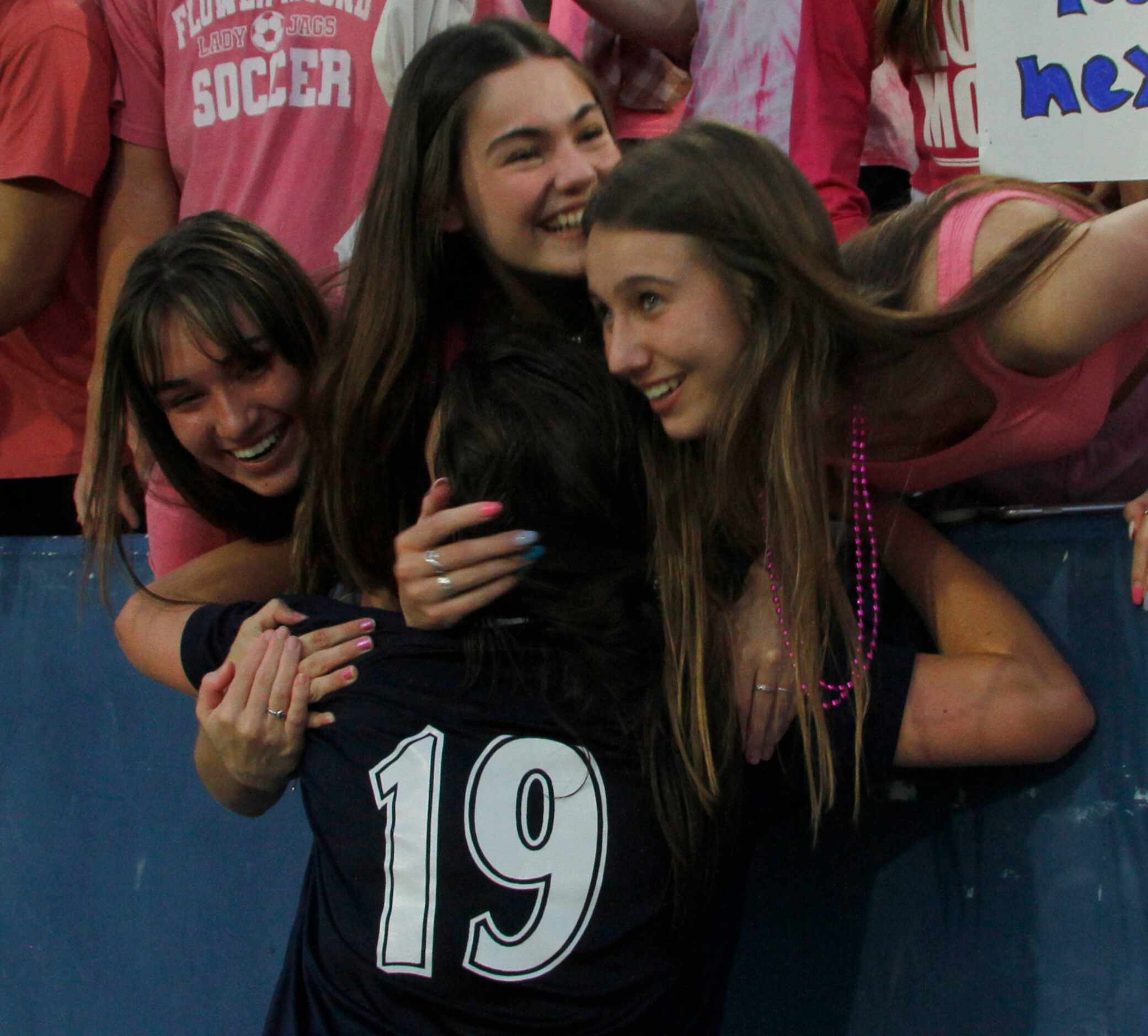 Flower Mound's Riley Baker (19) receives a group hug from fellow Flower Mound students in...