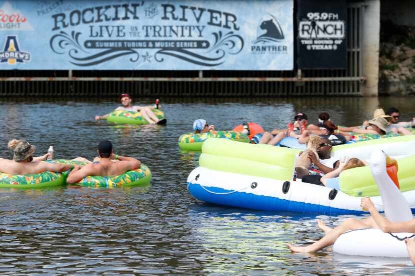 People in tubes float on the Trinity River while listening to the live music during the...