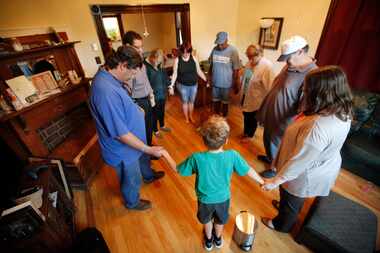 Nine year-old Isaac Schmersal (center) leads the prayer before dinner with residents and...