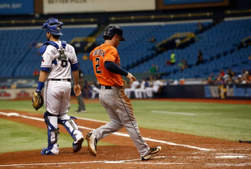 Alex Bregman of the Houston Astros crosses home plate in front of catcher Brett Nicholas of...